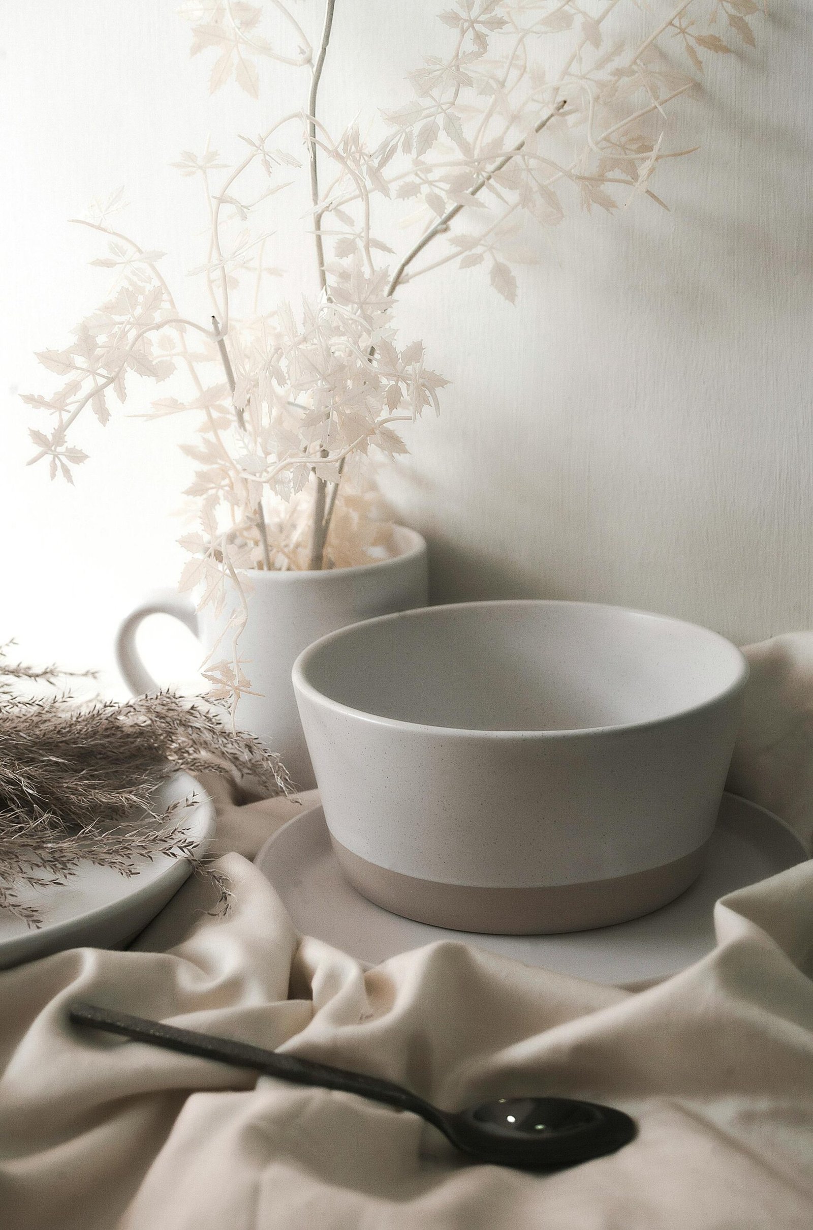 An elegant arrangement of ceramic tableware with delicate floral accents in soft, neutral tones.